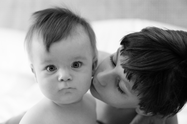 A brother kisses his baby brother.