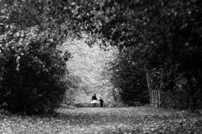 A brother and sister hold hands as they walk through a London Park.