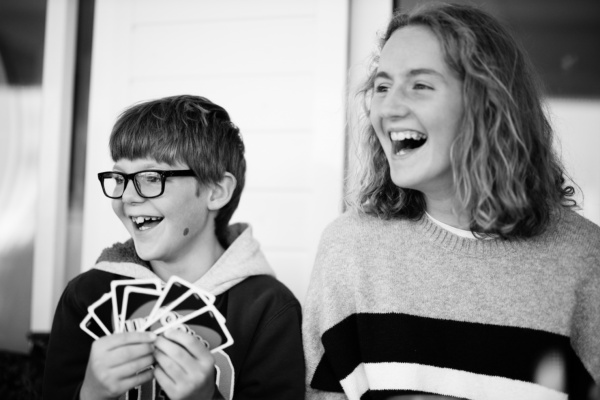 A brother and sister play cards together.