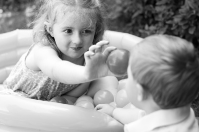 A brother and sister play in a ball pit.