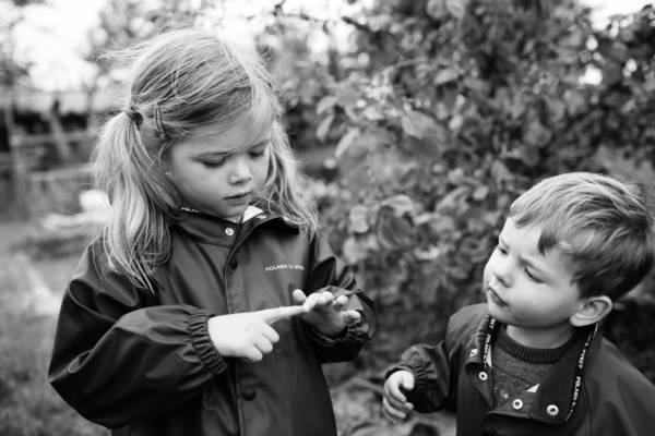 A brother and sister play in the garden together.