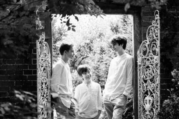 Brothers in white shirts pose in a doorway.