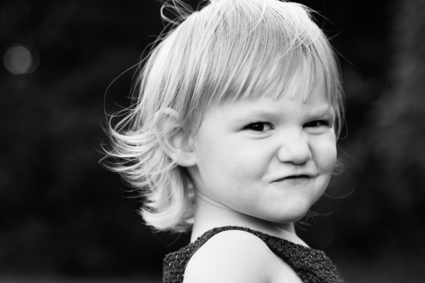 Black and white portrait of a child with a cheeky grin.