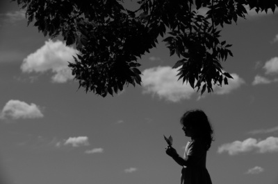 A child holds a leaf with a tree branch overhanging.