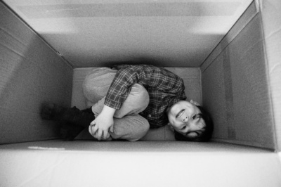 A child curls up inside a cardboard box.