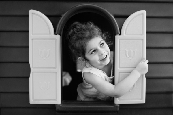 A child looks out of a toy window.