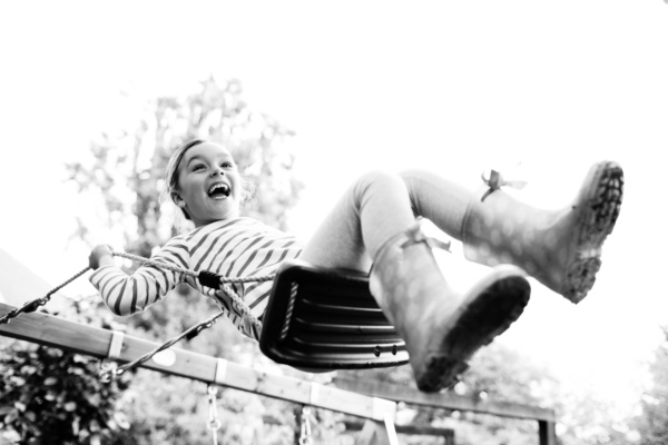 A child laughs on a swing, against the sky.