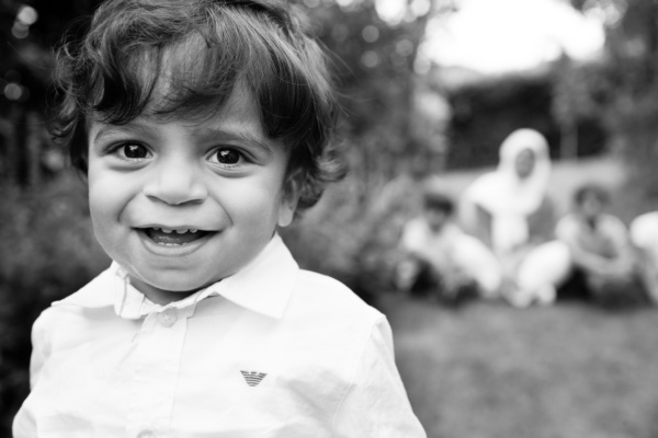 A child outdoors with family in the background.