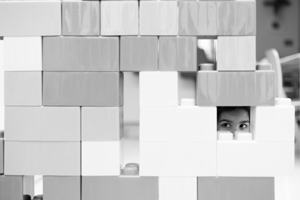 A child peeks out through giant Lego.