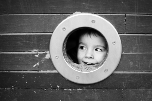 A child peeps out of a porthole.