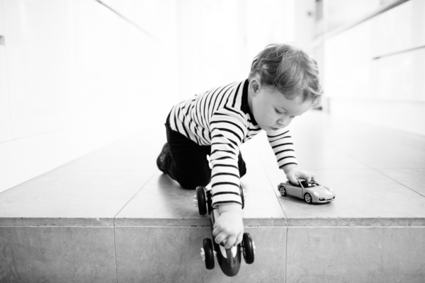 A child plays with toy cars on a stone floor.