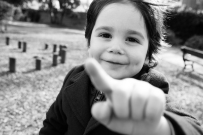 A child smiles and points at a camera.