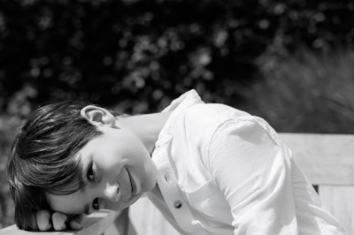 A child rests his head on a bench armrest.