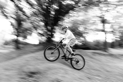 A child rides a bike over a small hill.