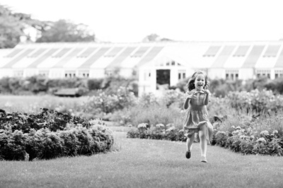 A girl runs through gardens as part of a family portrait session.