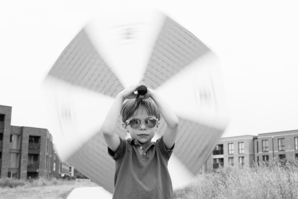 A child in sunglasses twirls an umbrella.