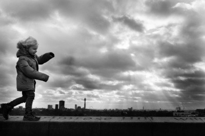 A child walks along the Thames with London in the background.