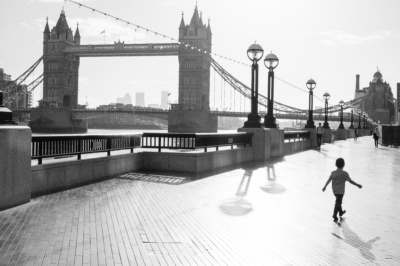 A child walks along London's South Bank with Tower Bridge in the background.