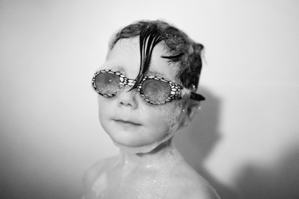 Child wears goggles in a bubble bath.