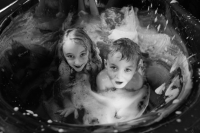 A brother and sister play in bubbles.