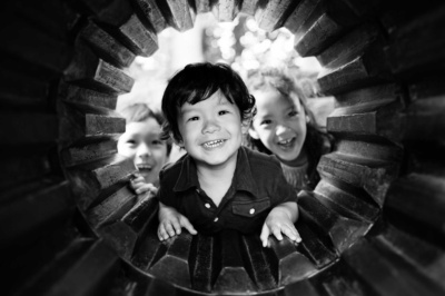 Three children look through an opening and smile.