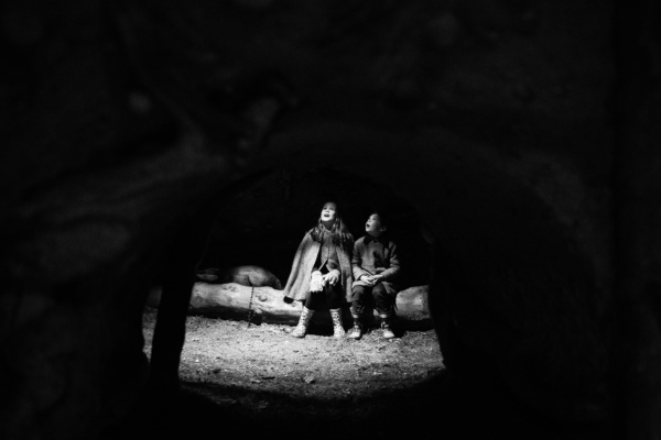 Children sit together in a patch of light.