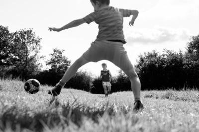 Children play football in a grassy field.