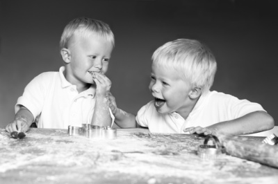 Two boys roll out pastry together.