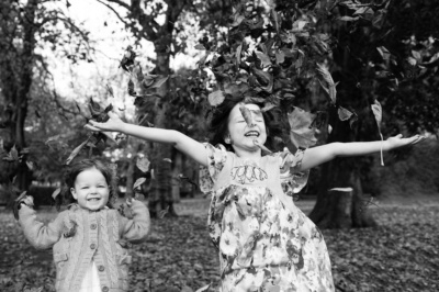 Children throw leaves in a London autumnal family portrait shoot.