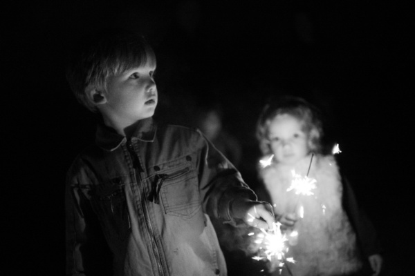 Children wave sparklers at night