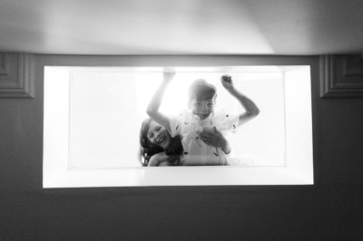 Siblings laugh together in black and white portrait.