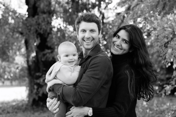 Parents and their baby cuddle in a London park as part of a vacation portrait shoot.