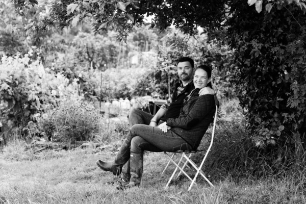 A mother and father sit together under a tree.