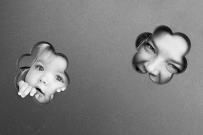 A mother and daughter peep out of flower-shaped gaps on playground equipment.