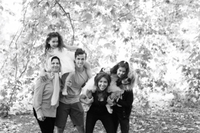 A family holds up children against a leafy background.