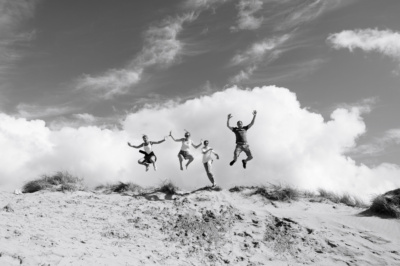 Family of four jumps into the air at the beach.