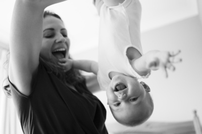 A mother suspends a giggling baby in the air.