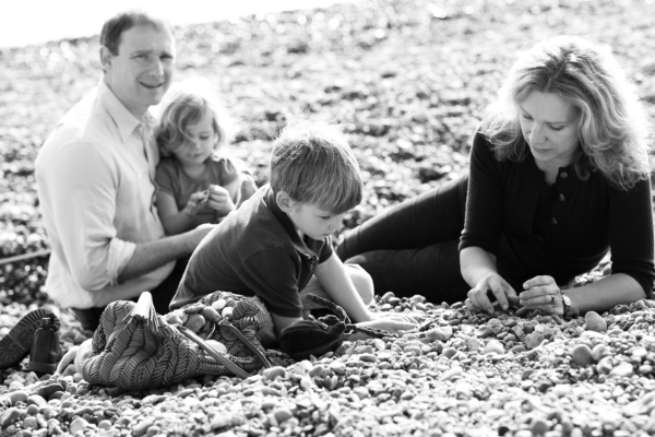 Family of four plays on a pebble beach.