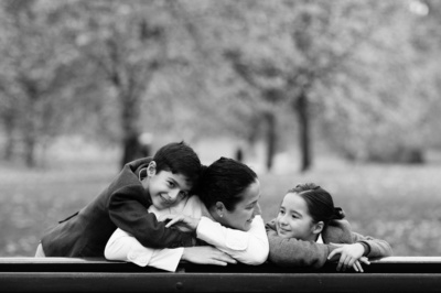 A mother and her two children hug on a park bench as part of a London portrait shoot.