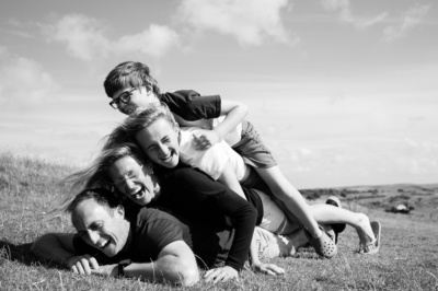 A family piles on each other for an outdoor portrait in black and white.