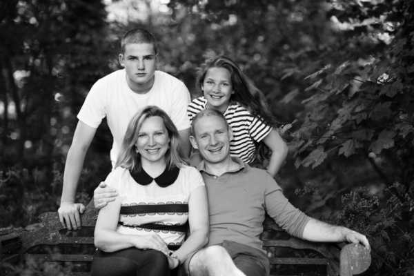 A family portrait with teenage offspring using a garden bench.