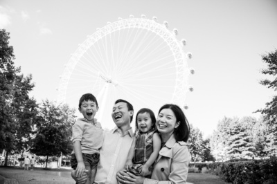 A family of four laugh together in front of the London Eye.