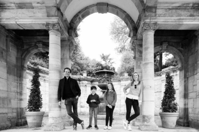 A family portrait of four framed by a stone archway.