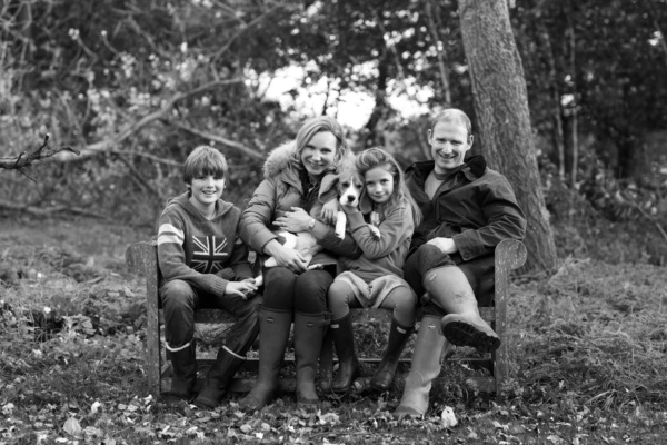 A family rests on a garden bench with their dog.