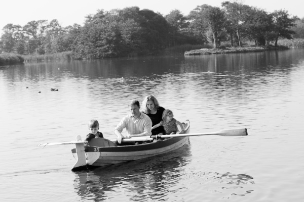 A family of four rows across the water.