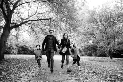 A family runs through the park in autumn.