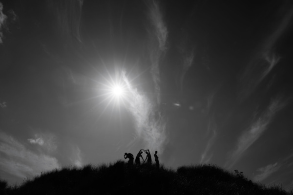 A family standing on a sand dune, silhouetted against the sky.