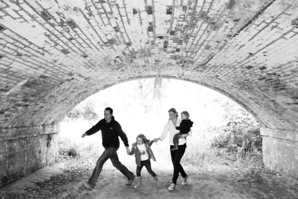 A family walks under a brick arch.