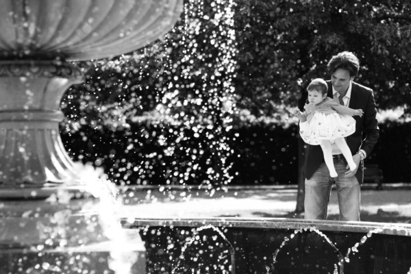 A father and his baby daughter near a fountain.