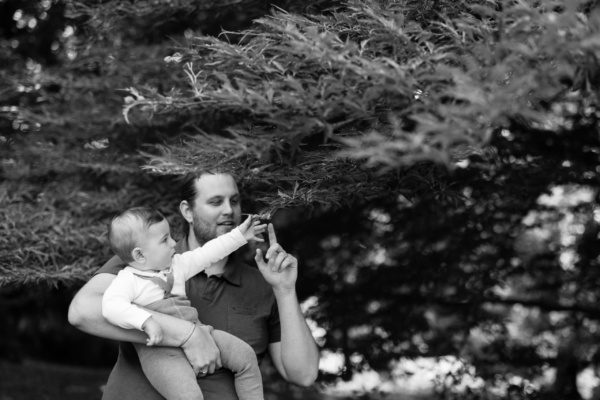 A father and baby touch a tree branch.